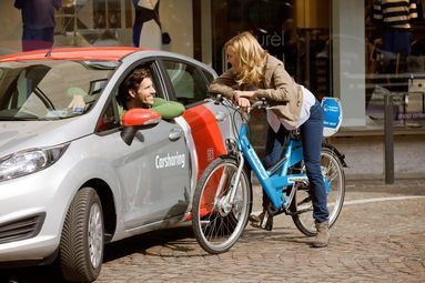 Frau mit RegioRadStuttgart Pedelec unterhält sich mit Mann im Flinkster Carsharing Auto