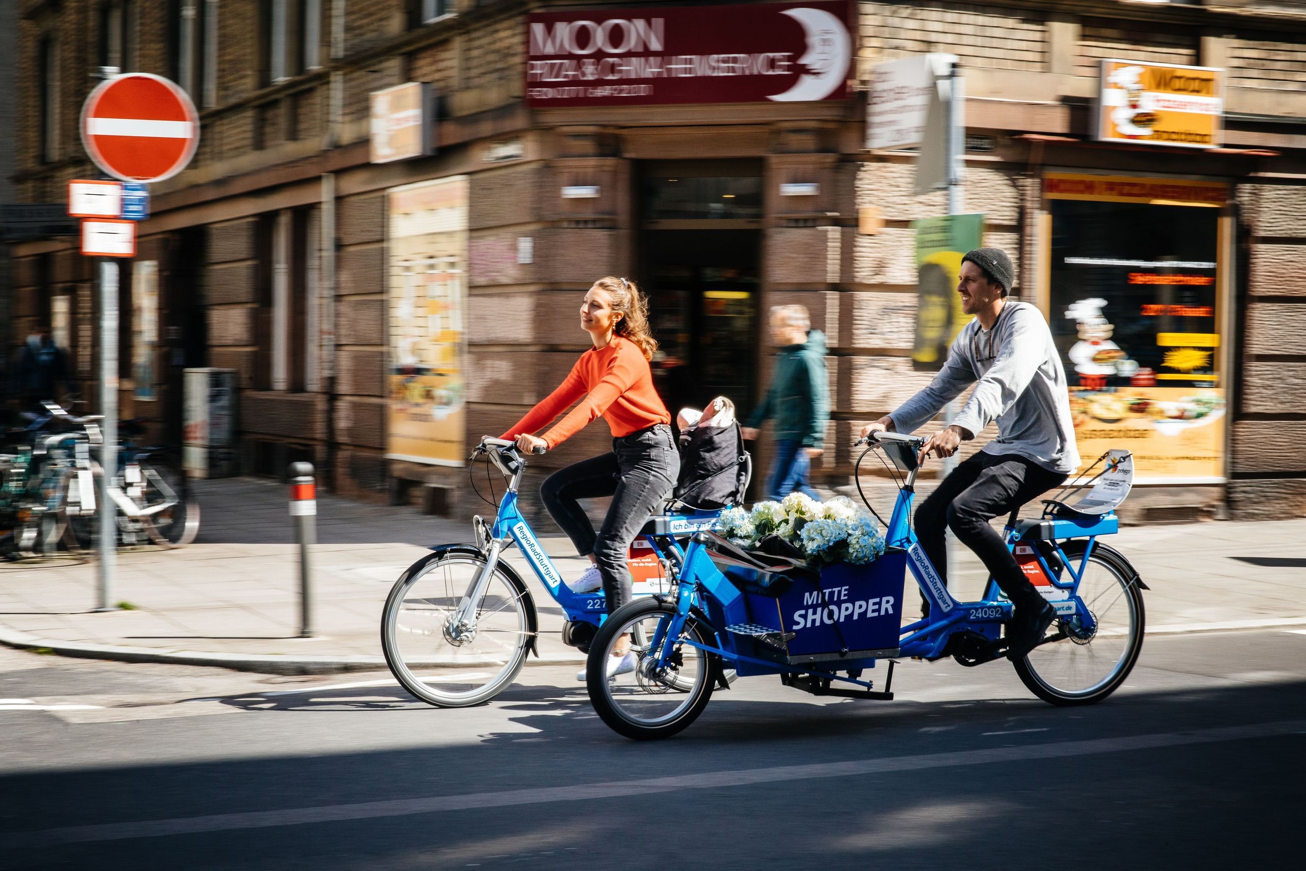 Two people riding RegioRadStuttgart bikes through the city.